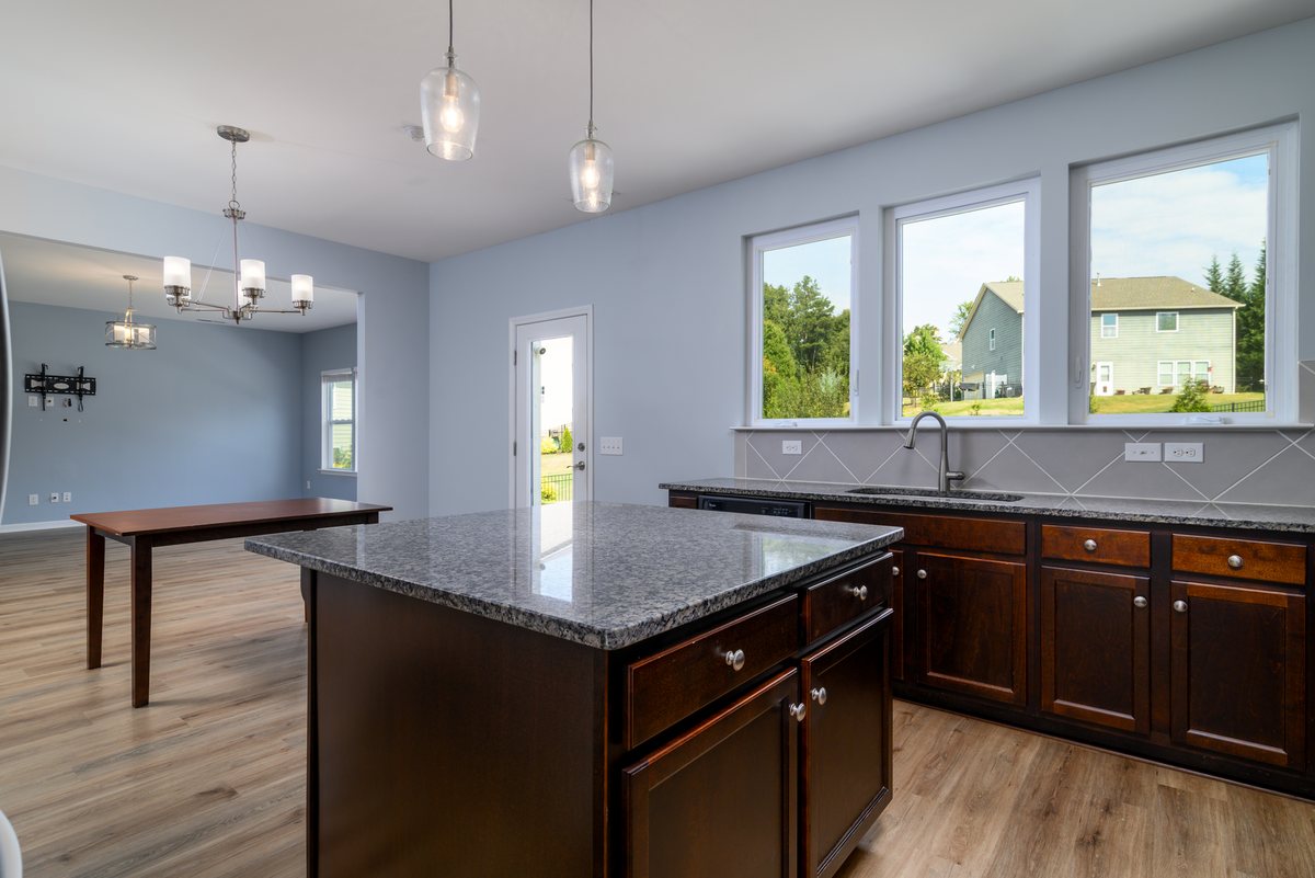 Kitchen at 7129 Dove Field Ln with granite island, dark wood cabinetry and large windows