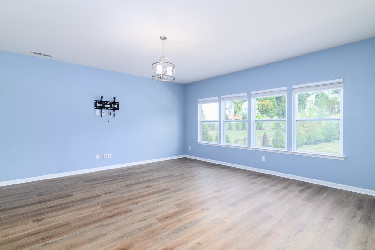 Sunlit living room at 7129 Dove Field Ln with wood-look floors and a wall of windows overlooking the backyard